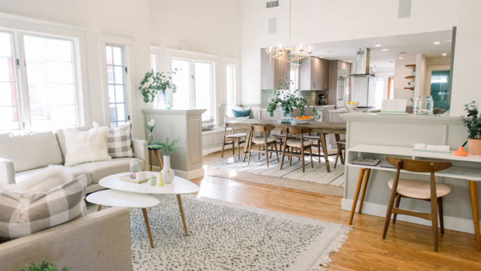 Interior view of bright, open-concept space with living room seating, dining table with chairs, and kitchen area with natural lighting