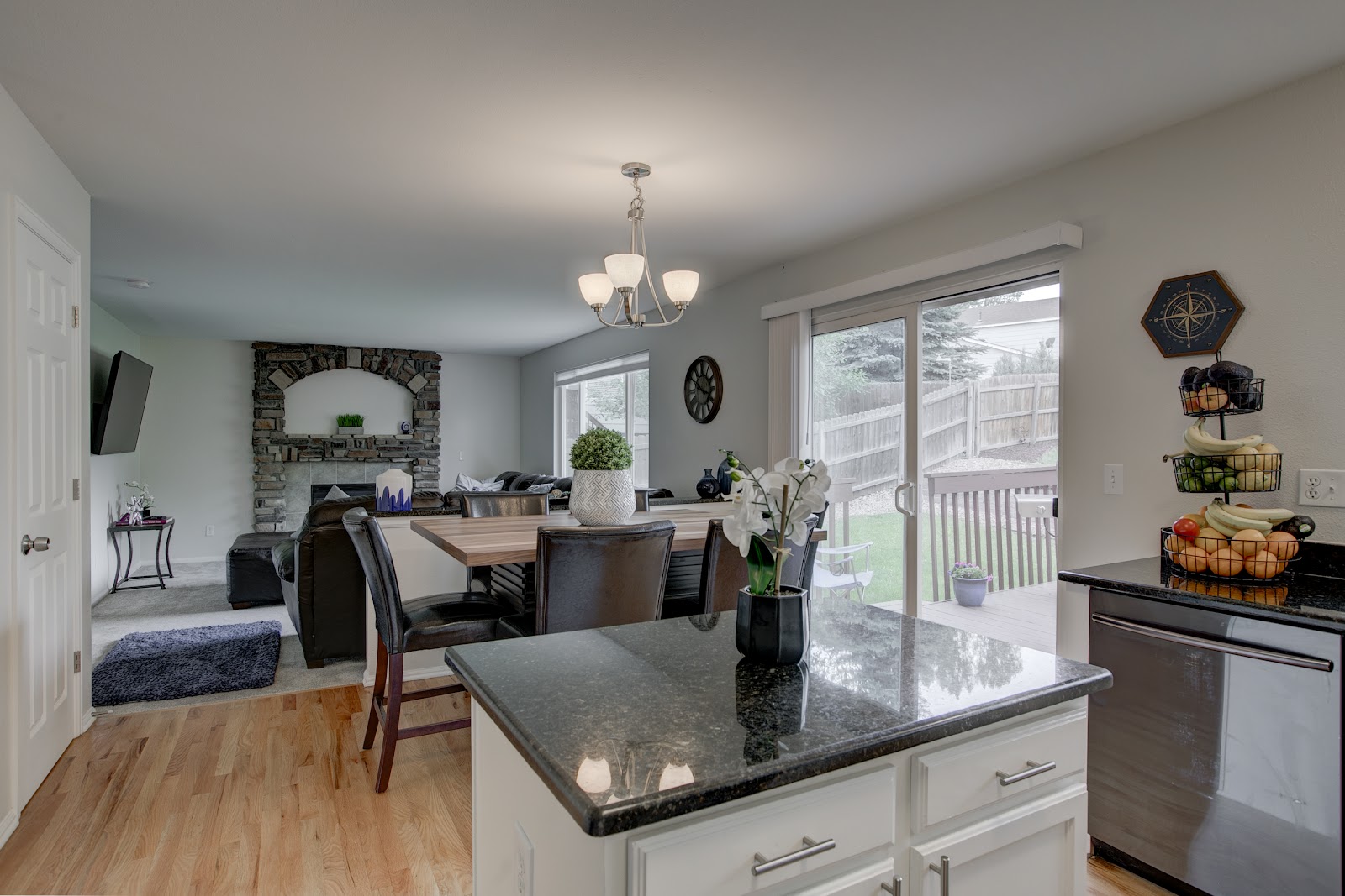 Interior kitchen and living area with granite island countertop, wood dining table, fireplace, and patio access