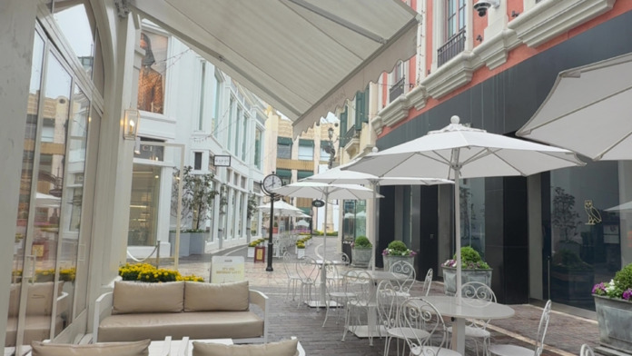 Interior courtyard with retractable awning, dining furniture, flowering planters, and historic architecture surrounding outdoor seating space