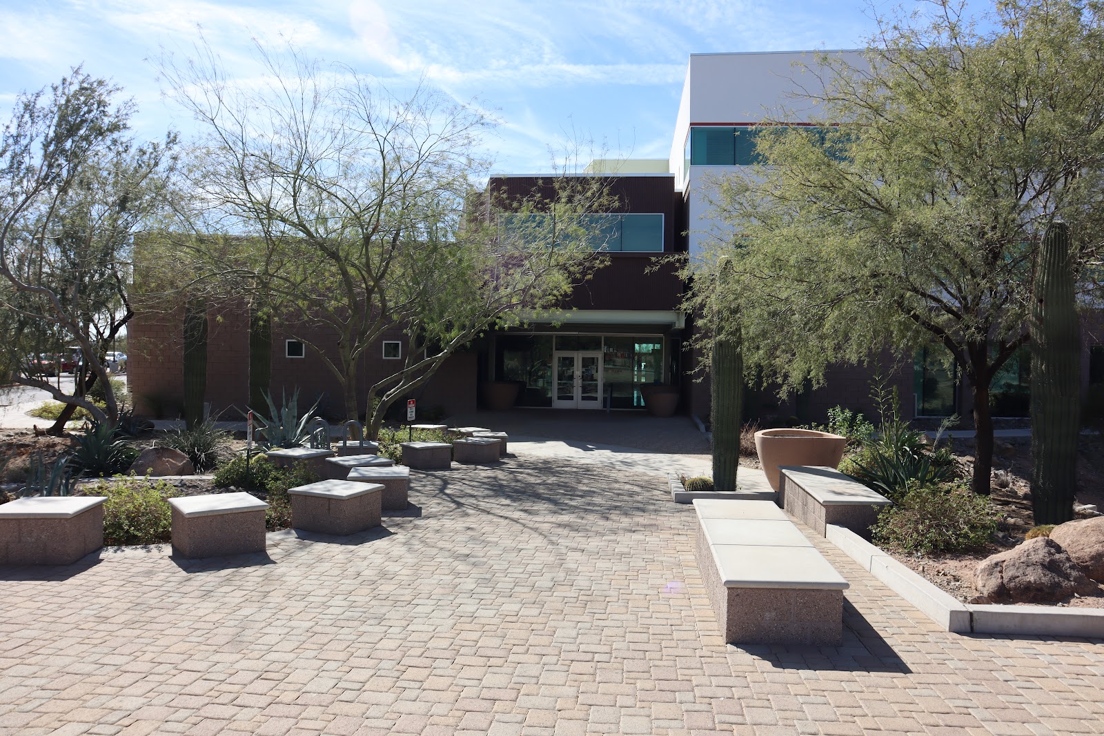 Exterior courtyard featuring paved plaza with benches, cacti landscaping, and desert plants