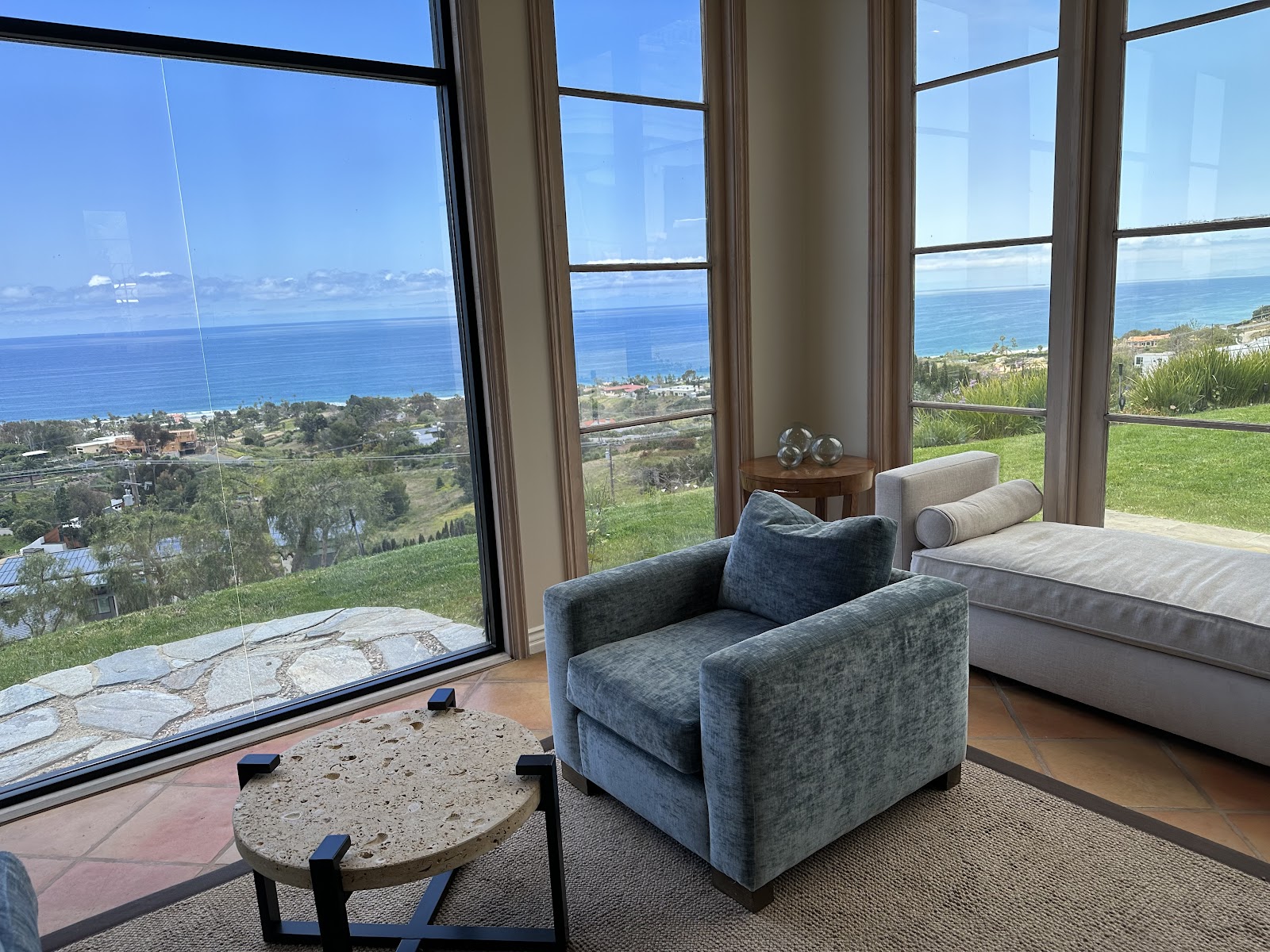 Interior bedroom featuring bed, armchair, windows with distant ocean and coastal landscape views