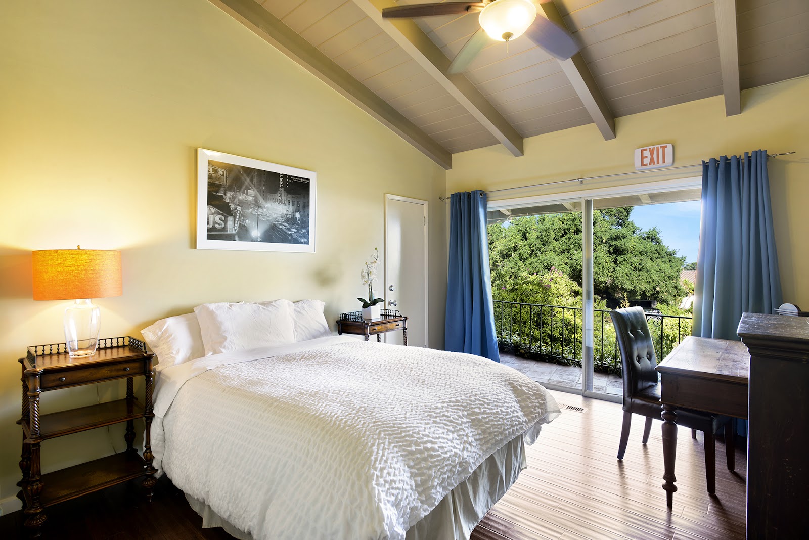 Interior bedroom featuring queen bed, bedside tables, balcony access, and hillside views