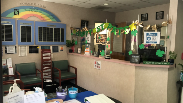 Interior reception area with sign-in desk, colorful decorative bulletin boards, seating chairs, and facility information displays