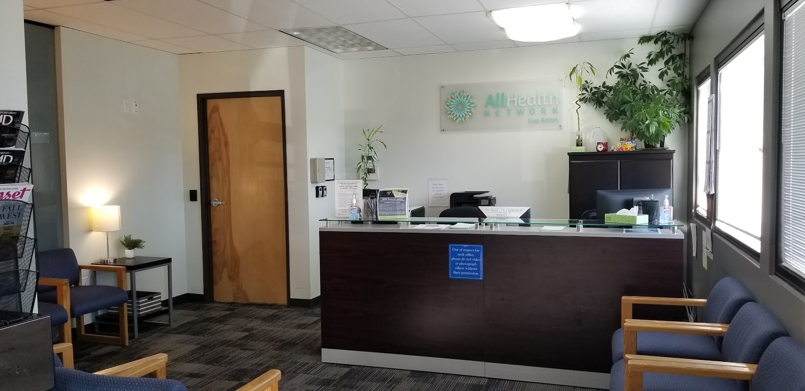 Interior reception desk with AllHealth Network signage, seating area, and check-in window