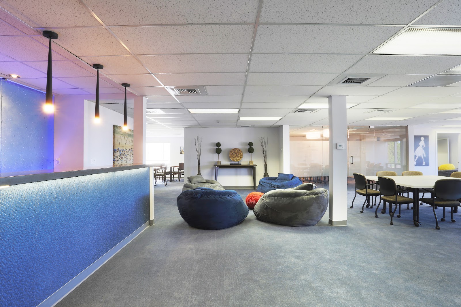 Interior common area with reception desk, blue-lit design element, decorative seating, and fireplace