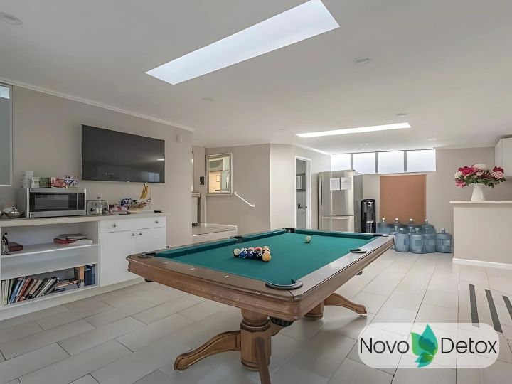 Interior recreation space featuring billiards table, wall-mounted television, white cabinetry, skylights, and hardwood accents.