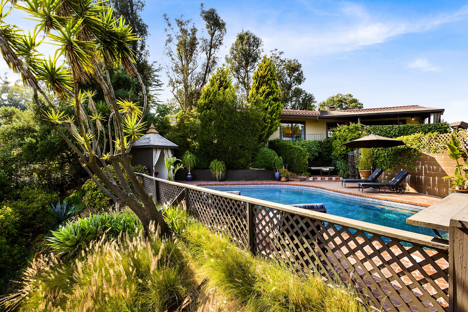 Exterior resort-style pool with loungers, landscaped grounds, and architectural building with mountain views