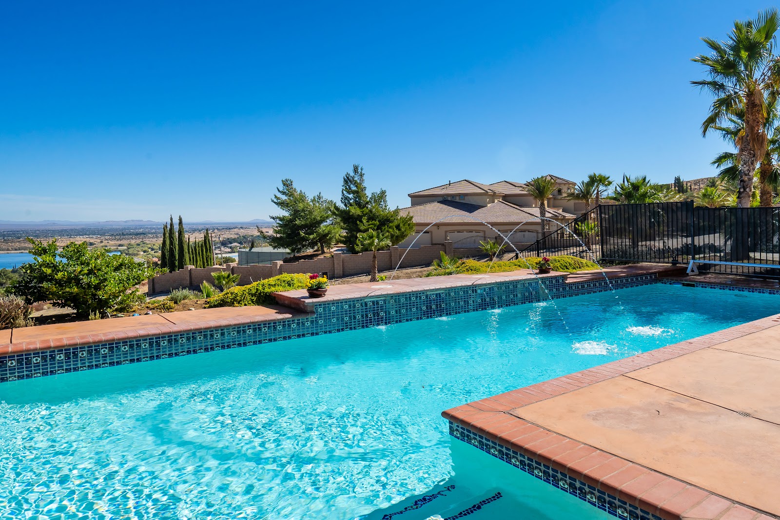 Exterior swimming pool with turquoise water, lounging areas, facility buildings, and landscape mountain views