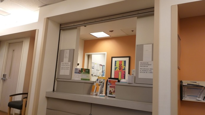 Interior service counter with orange accent wall, informational displays, and professional medical facility workspace