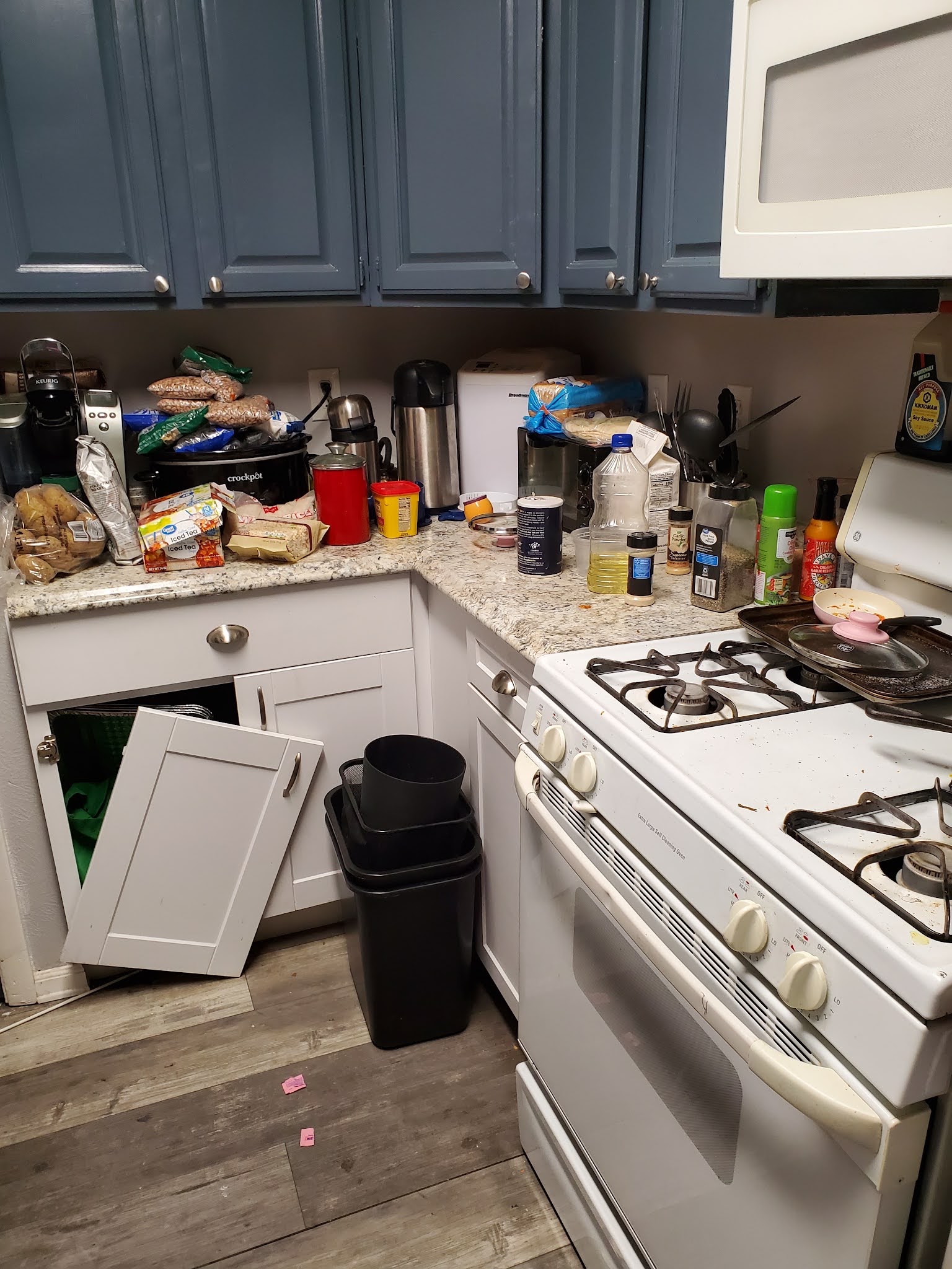 Interior kitchen with white and gray cabinetry, gas cooking range, granite countertops, and appliances.