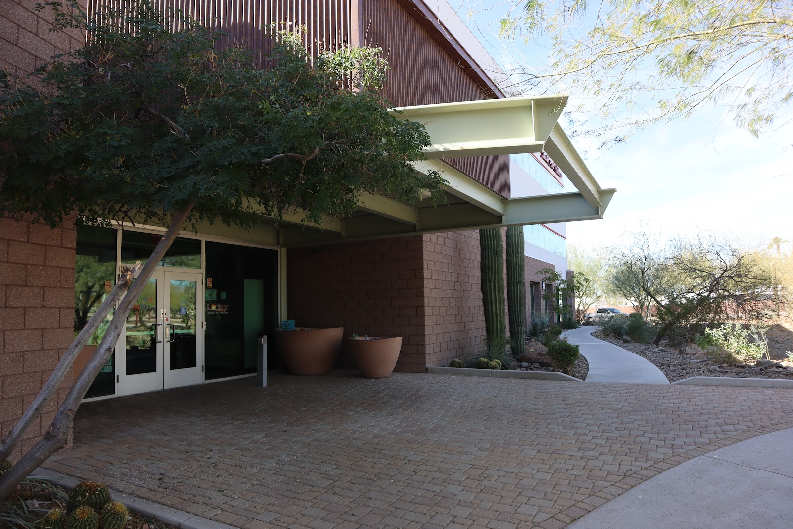 Exterior side entrance showing modern architecture, concrete pathway, and landscaped grounds