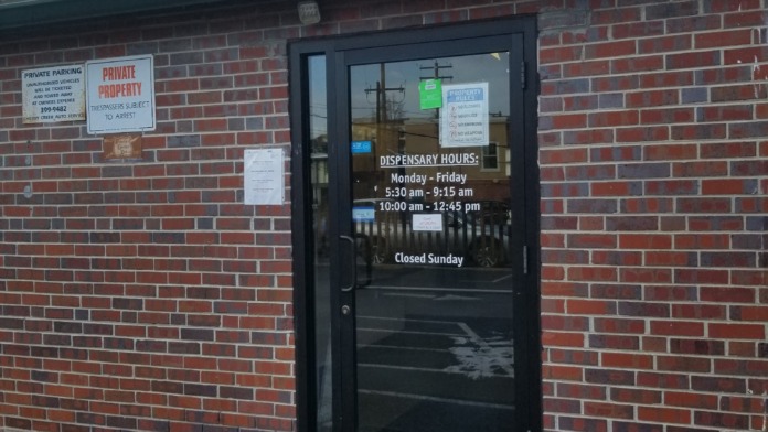 Exterior view of brick building side entrance with black door, parking and trespassing signs on brick facade
