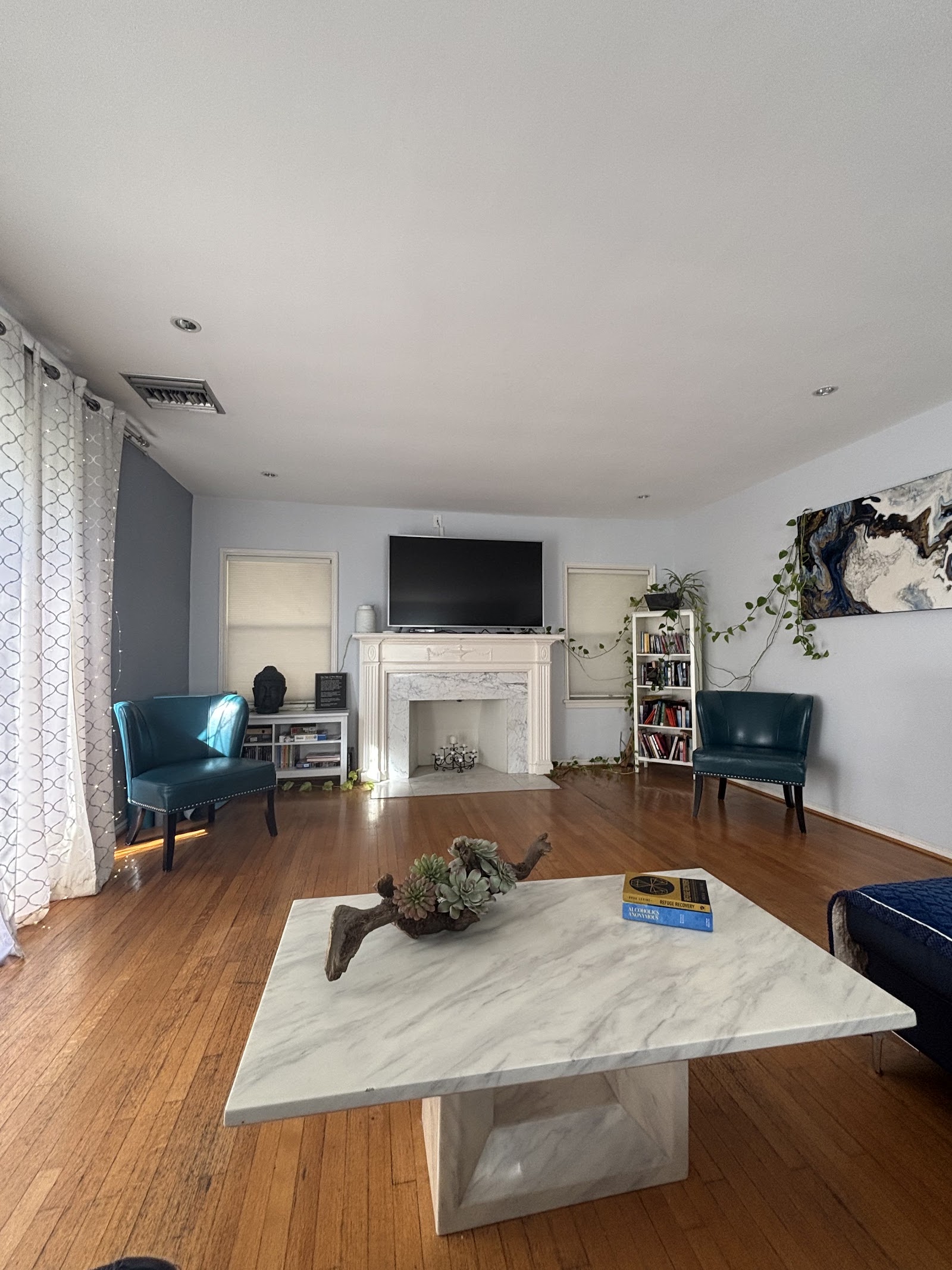 Interior living room featuring marble coffee table, upholstered chairs, fireplace, and contemporary artwork on walls
