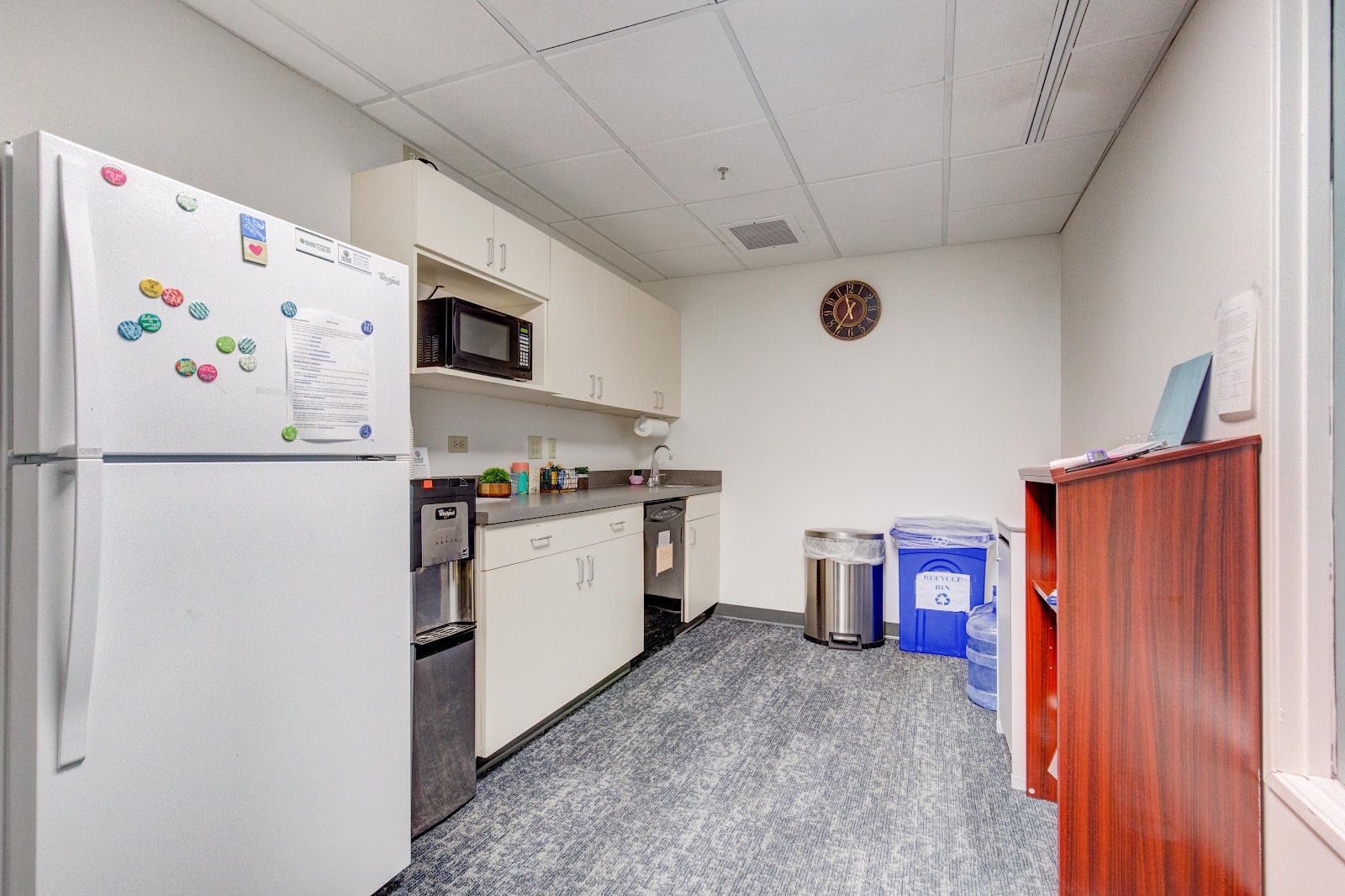 Interior break room with white refrigerator, microwave, cabinetry, sink, and gray tile flooring