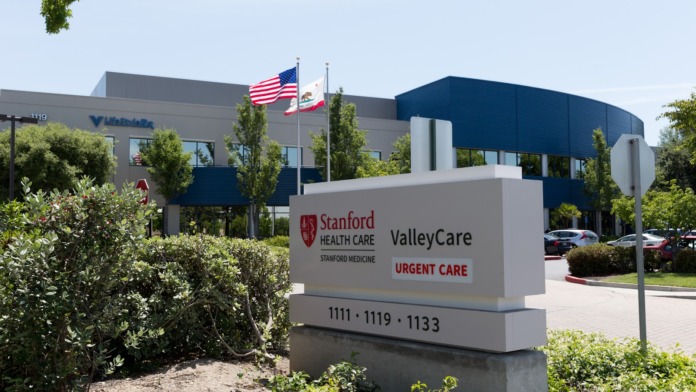 Exterior facility signage for Stanford HealthCare ValleyCare with address, landscaping, and American flags