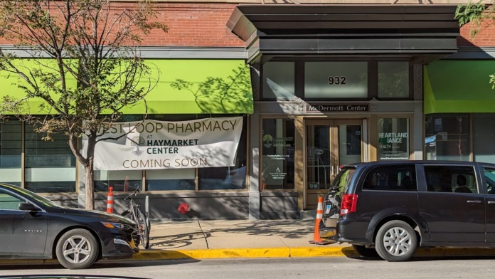 Exterior street view of brick building at 932 West Washington showing storefront windows, parked vehicles, and neighboring business signage.