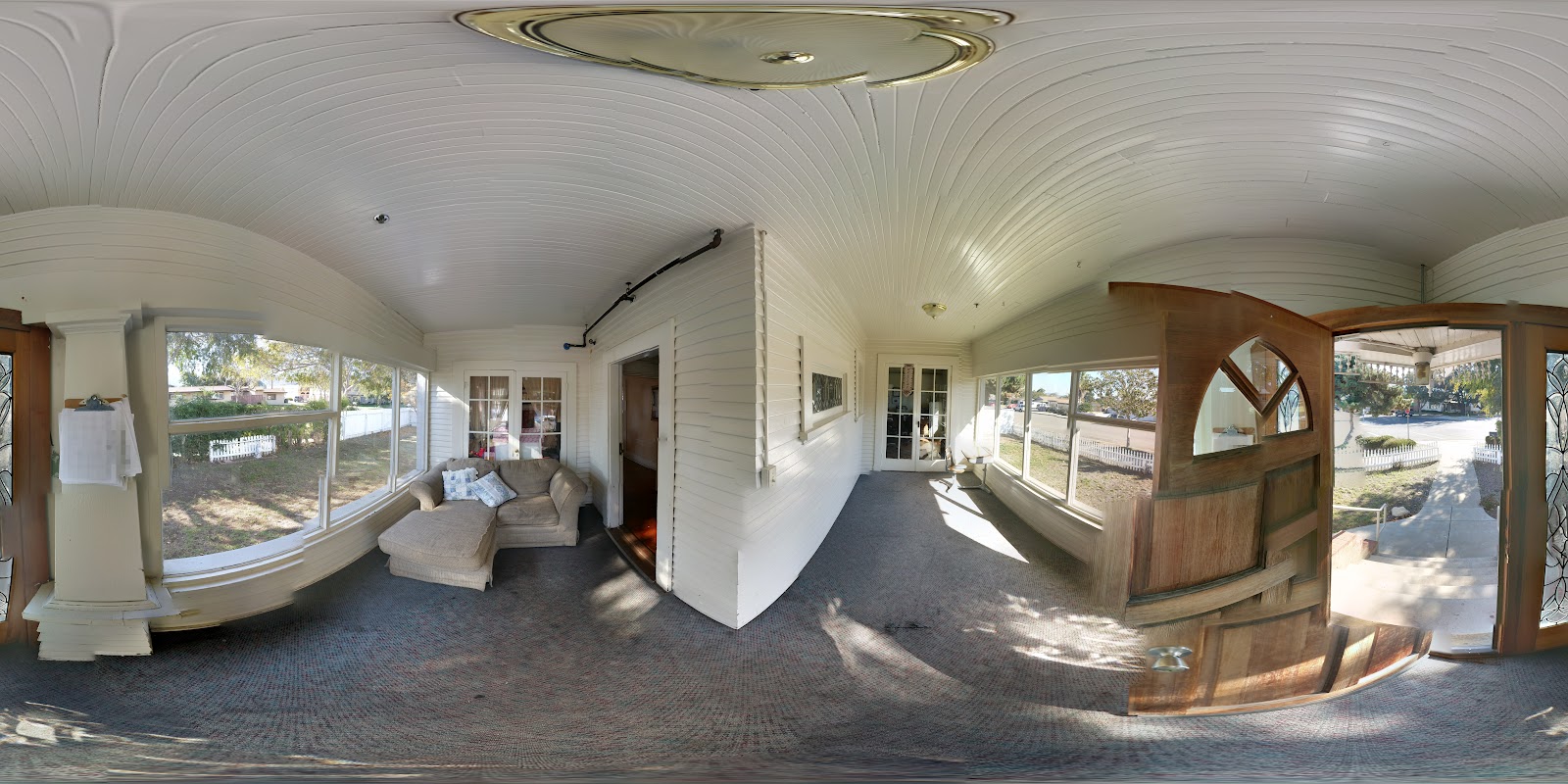 Interior sunroom featuring white walls, curved architectural elements, wooden flooring, and extensive window views of outdoor grounds