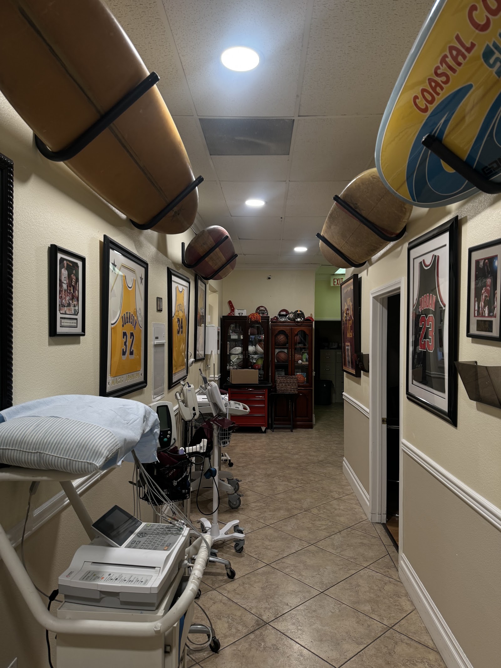 Interior treatment room with medical ultrasound equipment, examination bed, framed sports memorabilia, and professional healthcare setup