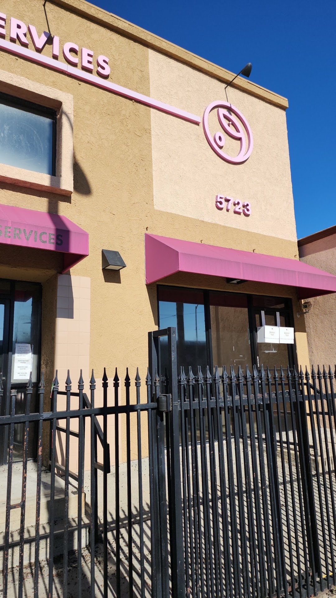 Exterior upper facade showing Mela Counseling Services text signage, facility logo, and architectural details against clear sky