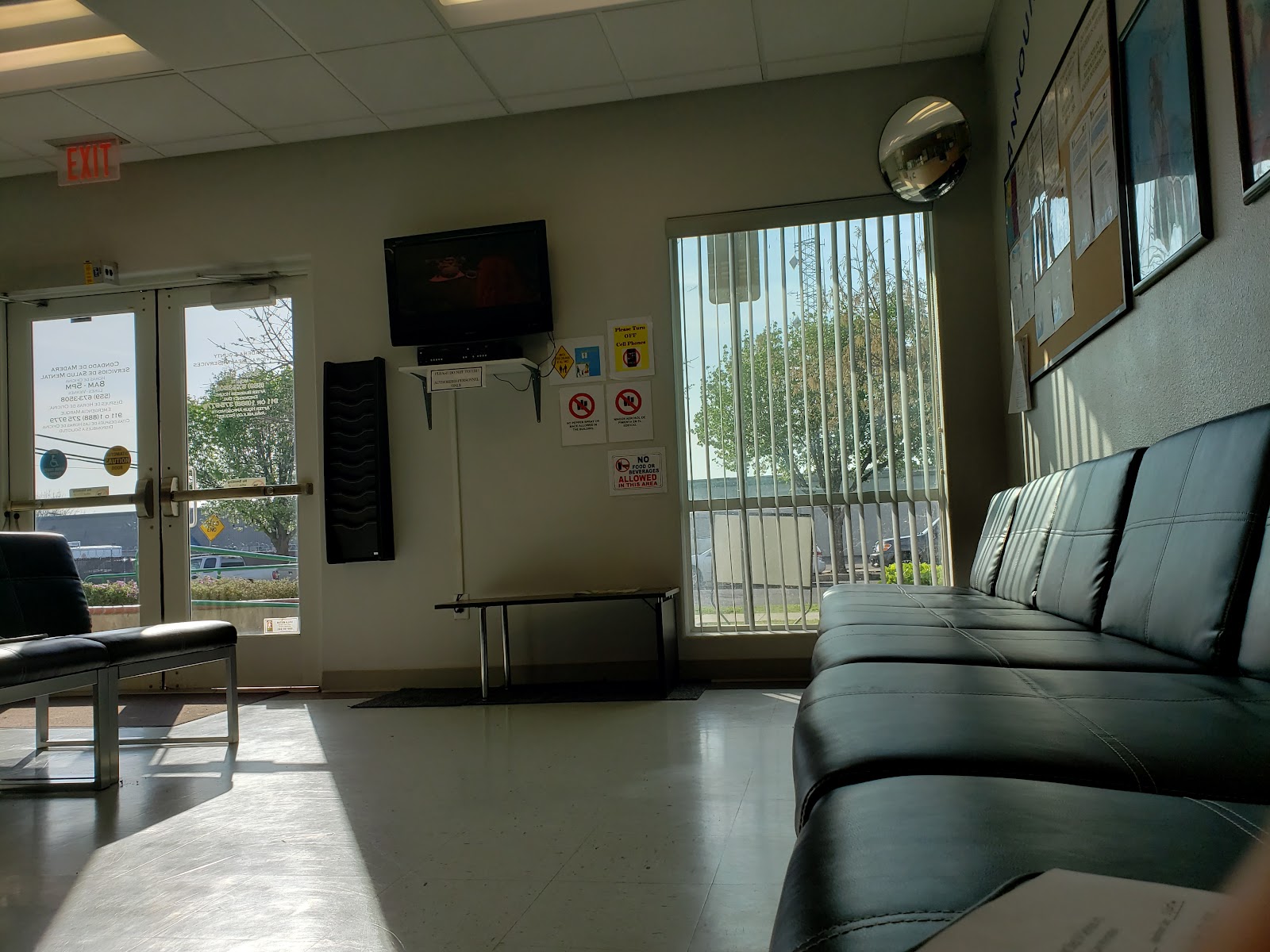 Interior waiting area with multiple black leather seating, large windows with natural light, and facility signage on walls
